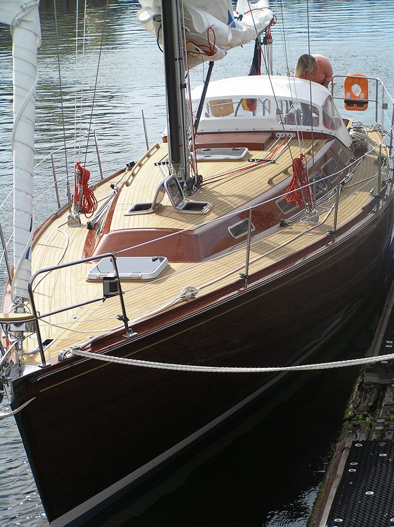 Segelyacht mit Teakdeck und dunklem Rumpf am Steg